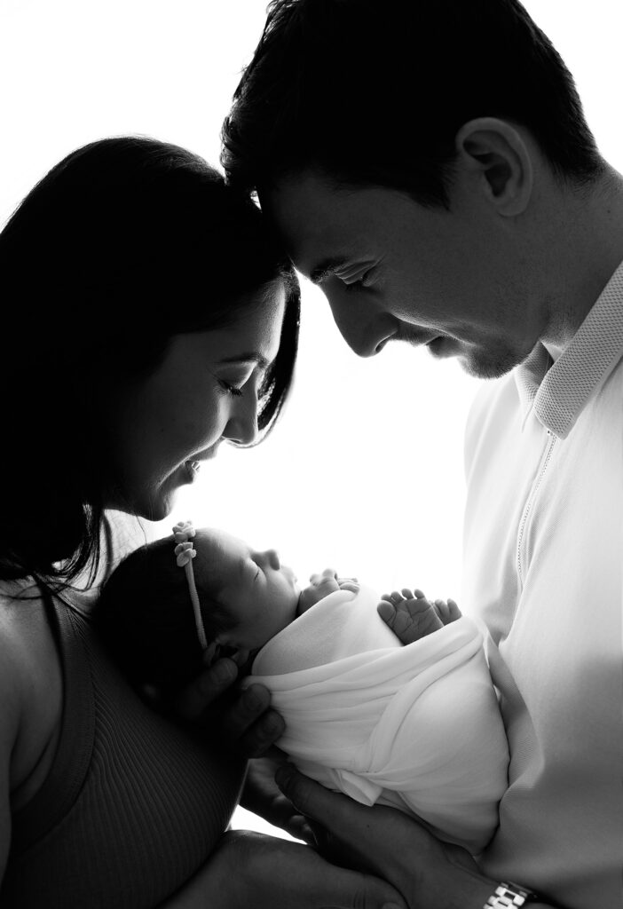 New Mum and Dad holding their newborn together in a photoshoot in Woking, Surrey