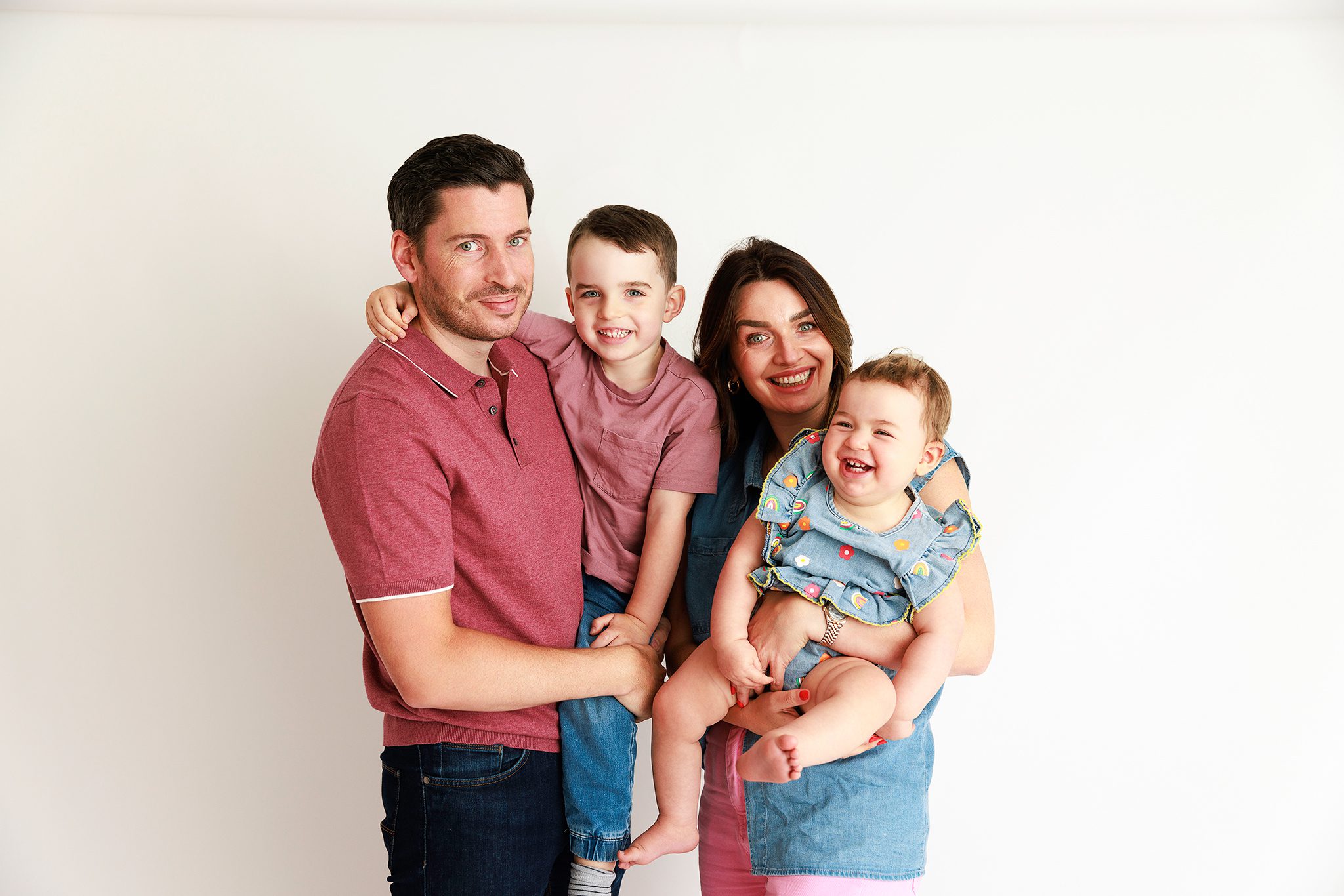 A family with 2 young children posing happily in a photoshoot in Woking