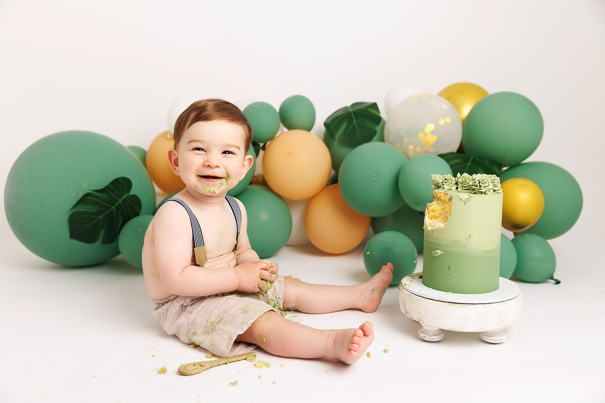 1st birthday cake smash session in Surrey with green balloons and real cake
