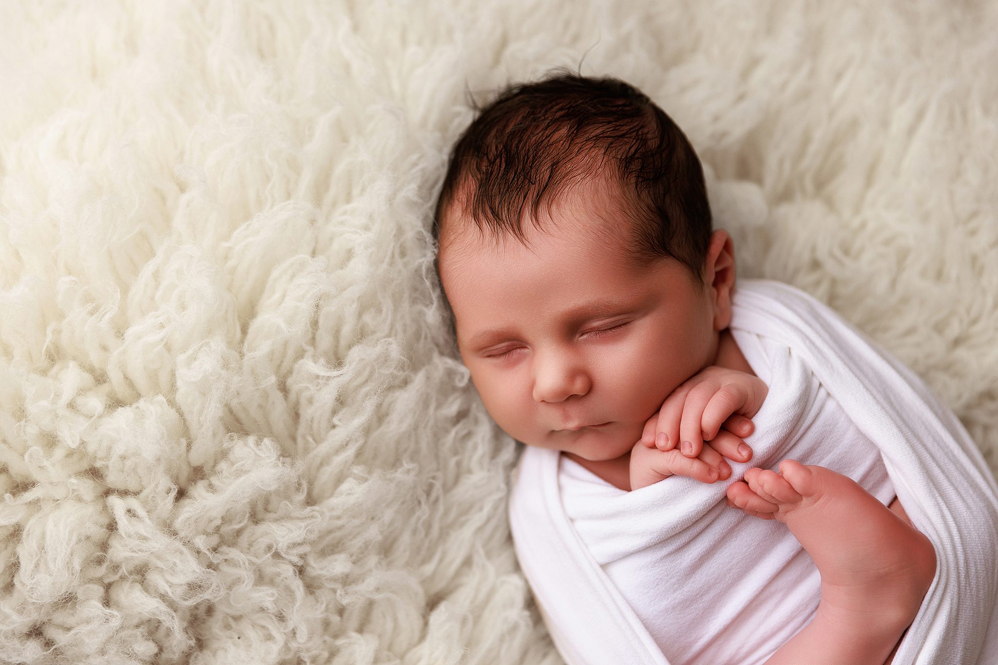 Liz Lockie Photography newborn boy wrapped up on a fluffy background asleep peacefully